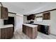 Dark wood kitchen island and cabinets, black appliances, and gray flooring at 10109 Old Spanish Trl, Polk City, FL 33868