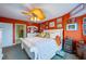 King-size bed in bright bedroom with orange walls and multiple pictures at 4670 Links Village Dr # D506, Ponce Inlet, FL 32127