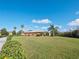 Single-story home with large backyard, lush landscaping, and a bright blue sky at 112 Sevilla Ct, Poinciana, FL 34759
