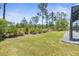 Grass lawn backyard with screened lanai and privacy from surrounding vegetation at 225 Sunset Point Dr, Ormond Beach, FL 32174