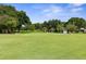 Putting green with yellow flags, surrounded by mature trees at 3404 Rexford Cir, Ormond Beach, FL 32174
