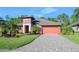 Beautiful two-story house with a reddish exterior, paver driveway and landscaping at 660 Aldenham Ln, Ormond Beach, FL 32174