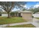 House exterior showcasing tan color scheme, garage, and a neatly kept lawn at 1300 Benton Lake E Dr, Deland, FL 32724