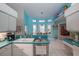 Open kitchen with teal countertops, white cabinets, and a view to the dining area at 3 Marsh Ridge Watch, Ormond Beach, FL 32174