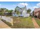 Front yard view of a light blue beach house with a white picket fence and tropical plants at 318 Vermont Ave, Daytona Beach, FL 32118