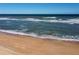 Aerial view of wide sandy beach with ocean waves at 89 S Atlantic Ave # 1401, Ormond Beach, FL 32176