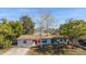 Single story home with red door and mature trees in the front yard at 1703 Hill St, Edgewater, FL 32132