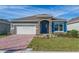 Single-story home with a gray exterior, blue door, and brick driveway at 437 Silver Palm Dr, Haines City, FL 33844
