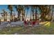 Lakefront fire pit surrounded by red chairs under the trees at 1241 W Lakeshore Dr, Clermont, FL 34711