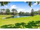 Serene pond with a stone bridge, lush green grass, and mature trees at 26142 Avenida Las Colinas # 2B, Howey In The Hills, FL 34737