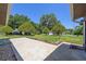 Front yard view showing a paved driveway, landscaping, and mature trees at 9930 County Road 114B, Wildwood, FL 34785