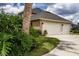 Two-car garage with a driveway and lush landscaping at 29334 David Ct, Tavares, FL 32778