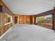Bright living room with wood paneling, large windows, and neutral carpeting at 304 E Noble Ave, Bushnell, FL 33513