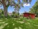 Red storage shed nestled in a green backyard at 304 E Noble Ave, Bushnell, FL 33513