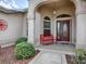 Inviting front porch with red bench, arched entryway and landscaping at 1751 Ashwood Run, The Villages, FL 32162