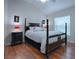 Bedroom with hardwood floors, a dark wood post bed, and red accent lamps at 1751 Ashwood Run, The Villages, FL 32162