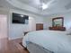 Main bedroom with wood floors, large TV, and ensuite access at 1751 Ashwood Run, The Villages, FL 32162