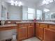 Double vanity bathroom with wood cabinets and a large mirror at 1751 Ashwood Run, The Villages, FL 32162