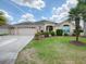 One-story house with beige exterior, two-car garage, and lush landscaping at 1751 Ashwood Run, The Villages, FL 32162