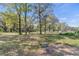 Open land with mature trees and a small house in the background at 26711 County Road 33, Groveland, FL 34736