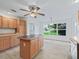 Kitchen with light wood cabinets, island, and window overlooking backyard at 102 Costa Mesa Dr, The Villages, FL 32159