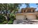 Two-car garage with stucco exterior and lush landscaping at 23 Camino Real Blvd # 23, Howey In The Hills, FL 34737