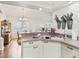Kitchen with white cabinets, corner sink and view into dining area at 1405 W Schwartz Blvd, The Villages, FL 32159
