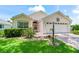 Charming light-colored house with landscaping, a brick driveway and a two-car garage at 1405 W Schwartz Blvd, The Villages, FL 32159