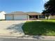 Single-story home with three-car garage and well-maintained lawn at 12046 Ne 51St Cir, Oxford, FL 34484