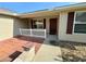 Front entrance with brick patio, small white fence, and landscaping at 12046 Ne 51St Cir, Oxford, FL 34484