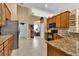 Modern kitchen with stainless steel refrigerator, granite counters, and wood cabinets at 13144 Coldwater Loop, Clermont, FL 34711