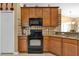 View of kitchen with black appliances, wood cabinets, and granite countertops at 13144 Coldwater Loop, Clermont, FL 34711