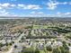 Aerial view of a neighborhood with houses, trees, and a golf course near a lake at 13144 Coldwater Loop, Clermont, FL 34711