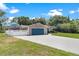 House exterior featuring a teal garage door and white fence at 12270 Virginia Dr, Leesburg, FL 34788