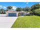 House exterior showcasing a teal garage door and lush landscaping at 12270 Virginia Dr, Leesburg, FL 34788