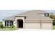 Two-story house with beige exterior, three-car garage, and landscaping at 2368 Juniper Berry Dr, Minneola, FL 34715