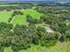 Aerial view of a property showcasing a large field and tree-lined areas at 2027 Cr 232, Wildwood, FL 34785