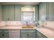 Light teal kitchen cabinets, granite countertops, and a double sink at 601 N Mcdonald St # 608, Mount Dora, FL 32757