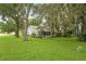 House nestled in a lush green backyard with large trees at 131 Costa Mesa Dr, The Villages, FL 32159