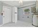 White tiled laundry room with storage cabinet and window at 6919 Fern Cir, Leesburg, FL 34748