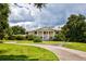 Brick home with circular driveway, manicured lawn, and mature trees at 6779 Clayton St, Mount Dora, FL 32757