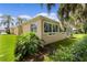 Tan house exterior with large windows and green landscaping at 7151 Se 173Rd Arlington Loop, The Villages, FL 32162