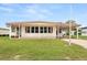 Front view of a single-story manufactured home with a covered carport and well-maintained lawn at 1209 Apache Cir, Tavares, FL 32778