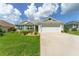 House exterior featuring a two-car garage and well-manicured lawn at 11394 Zimmerman Path, Oxford, FL 34484