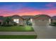 Tan two-story house with three-car garage and landscaped yard at 3506 Mulberry Grove Loop, Leesburg, FL 34748