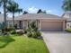House with a landscaped lawn, attached garage, and palm trees in Florida at 616 Cokesbury Dr, The Villages, FL 32162