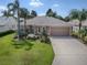 Single-story home with landscaped yard, attached garage, and palm trees at 616 Cokesbury Dr, The Villages, FL 32162