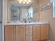 Bathroom with double sinks, light wood cabinets, and a large mirror at 616 Cokesbury Dr, The Villages, FL 32162