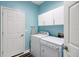 Laundry room with washer, dryer, cabinets, and light blue walls at 32915 Crooked Oaks Ln, Leesburg, FL 34748
