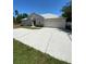 House exterior with light beige walls, attached garage, and a long driveway at 390 Colonade Ct, Kissimmee, FL 34758